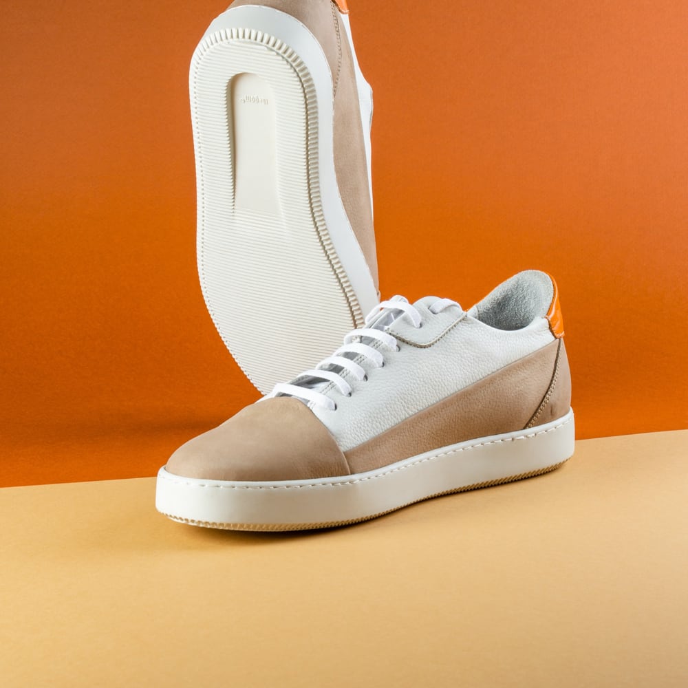Stylish white sneakers featuring vibrant orange details, ideal for a trendy look.